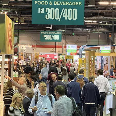 Private label buyers walk around the trade show floor in front of a booth