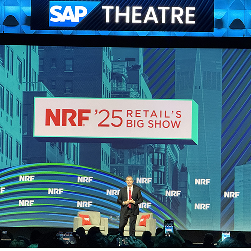 A man in a dark suit speaks on stage at NRF